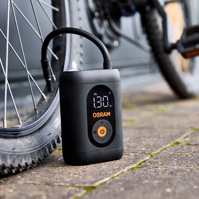 Osram TYREinflate 1600 står ved cykelhjul med tilsluttet slange, display viser 130