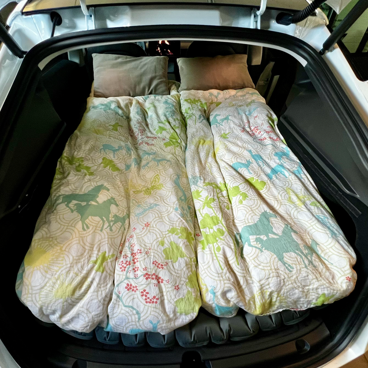 Luchtbed met beddengoed en kussens in de kofferbak klaar voor autovakantie