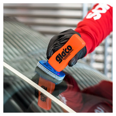 Hand met Glaco DX glasbeschermer op autoruit nabij wit tape