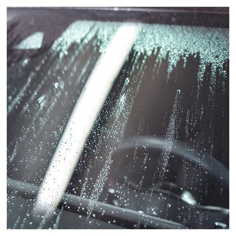 Ruit met waterparels en de ruitenwisser van de auto na Glaco-behandeling.