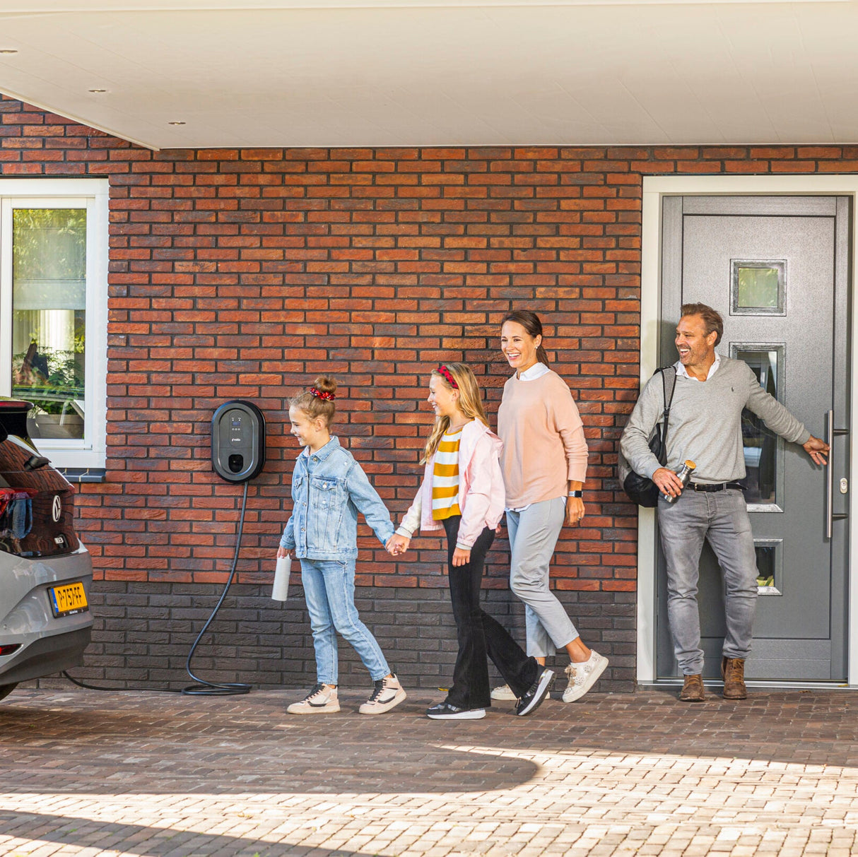 Familie komt thuis bij de Ratio laadpaal en elektrische auto, die is aangesloten