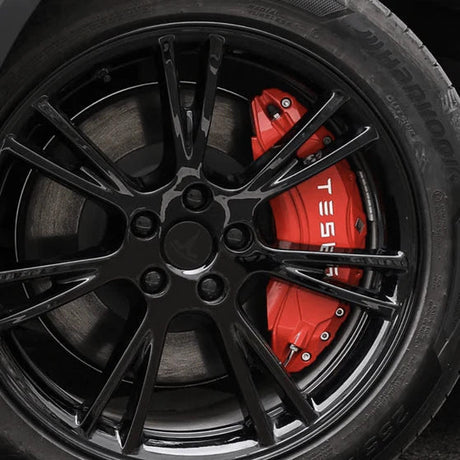 Rode remklauwhoezen met wit Tesla-logo op een zwarte velg.