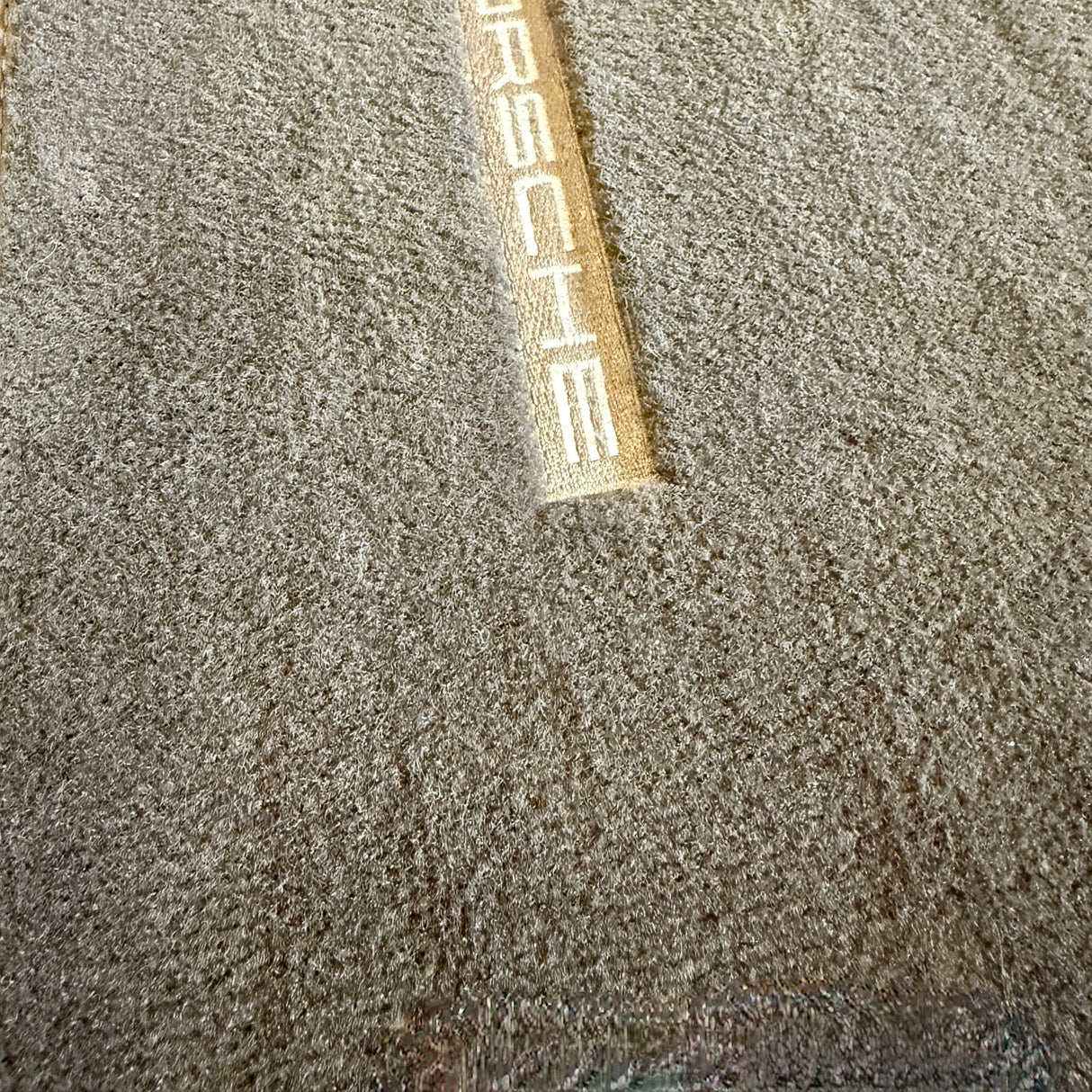 Na-foto van een schone automatten met Porsche-logo na gebruik van de stofzuiger