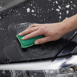 Hand wast auto met groene spons en zeepbellen.
