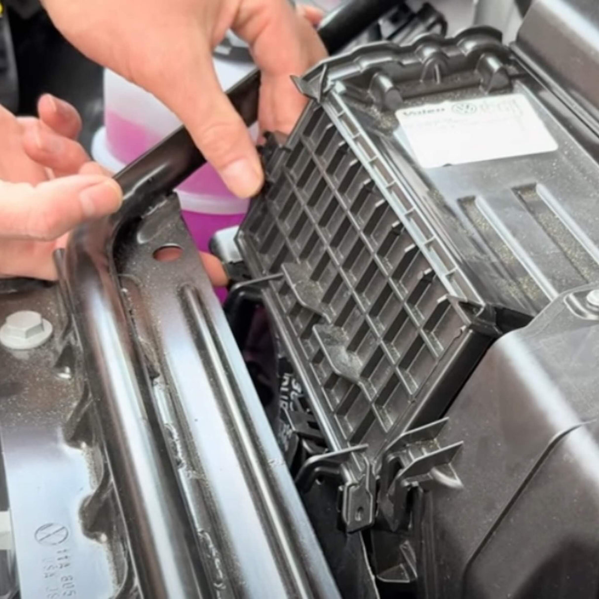 Persoon installeert een koolstoffilter in de motorruimte van een VW ID.3/4/5/6/7.