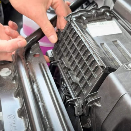 Persoon installeert een koolstoffilter in de motorruimte van een VW ID.3/4/5/6/7.