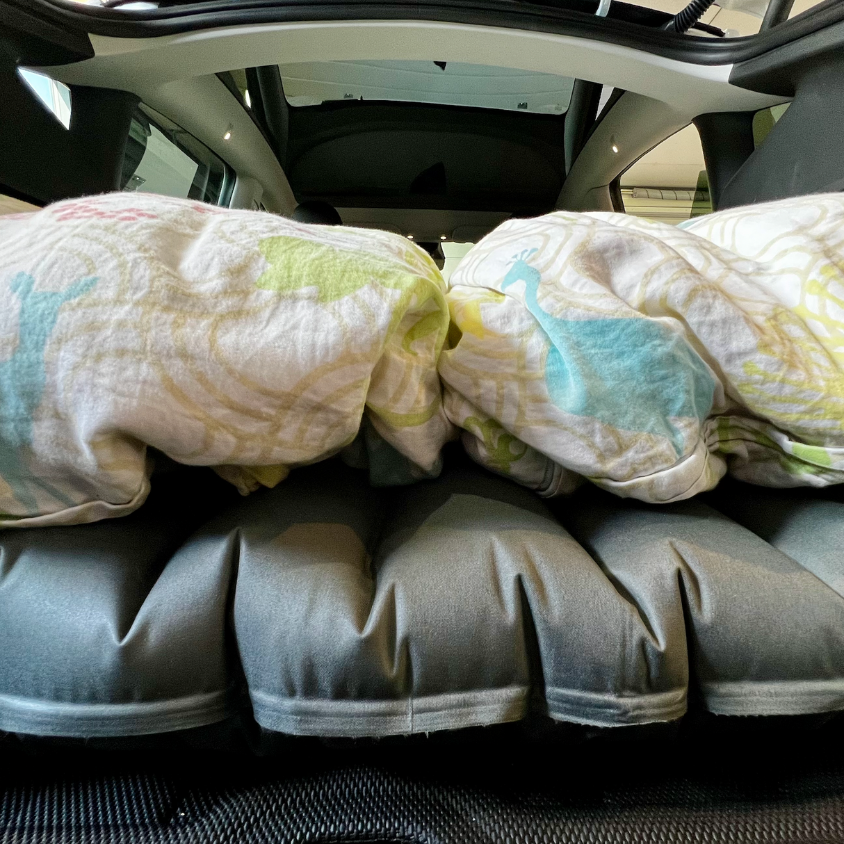 Luchtbed met beddengoed in de kofferbak van een Tesla Model Y voor een autovakantie.